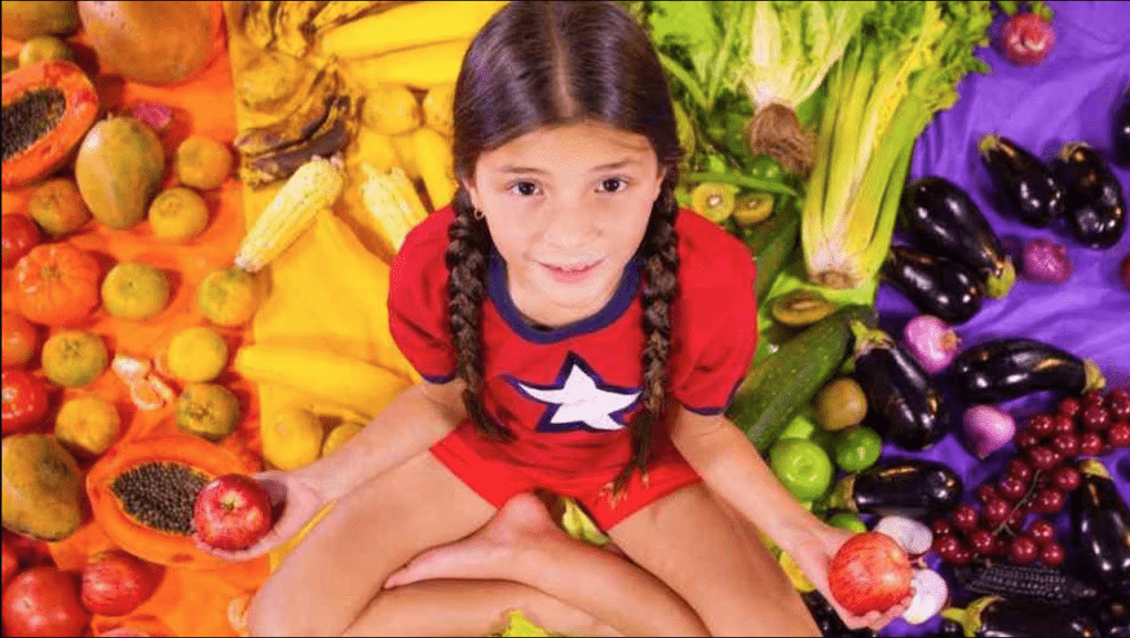 Niña sobre monton de frutas